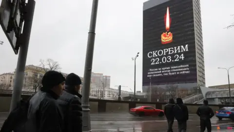 Getty Images Screens all around Moscow are showing images of a burning candle along with the Russian word "Skorbim" ("We mourn").