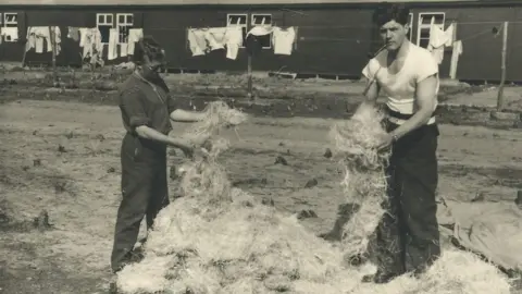 Gunn Family Alastair Gunn, right, stuffing fresh straw into bedding at Stalag Luft III