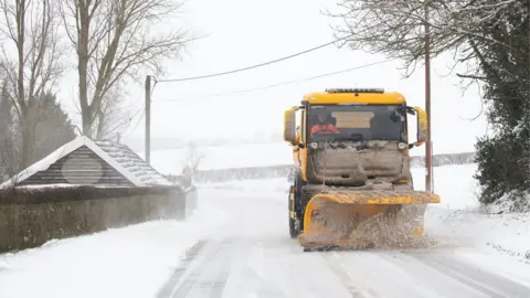 PA Media A snowplough clearing the road near Barham, Ipswich