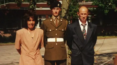 Family handout/PA Pte Sean Benton with his parents at his passing out at Pirbright Barracks in 1994