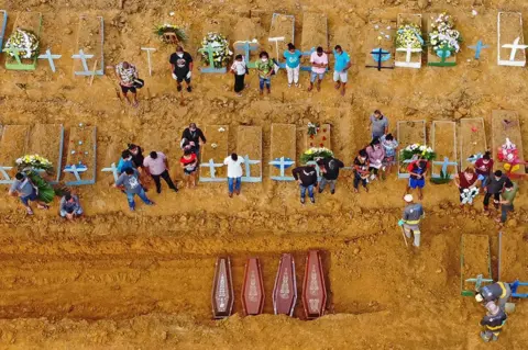 Michael Dantas / AFP A burial takes place at the Nossa Senhora Aparecida cemetery in Manaus, in the Amazon forest in Brazil.