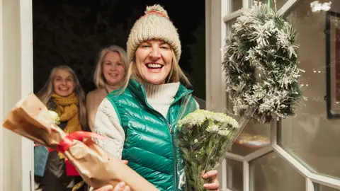 Getty Images Guests arrive at door bearing Christmas gifts