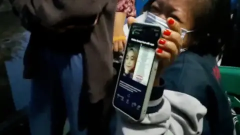 Widianingsih Lena's mother holding a photo of her daughter