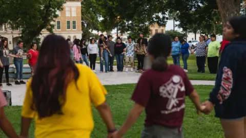 Getty Images People hold hands at a vigil in Uvalde