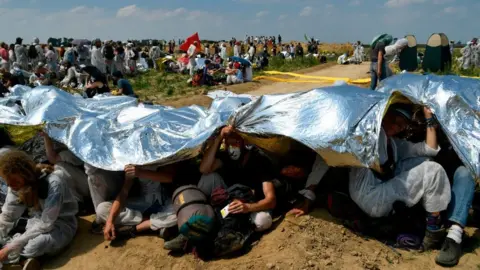 Getty Images Activists shielding themselves from the sun using a foil blanket