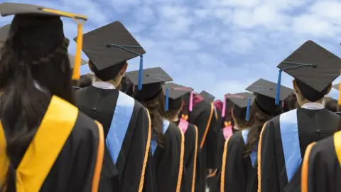 Getty Images Graduates in gowns looking to a blue sky