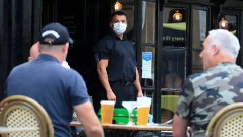 Getty Images A doorman wearing PPE outside a pub in Newcastle