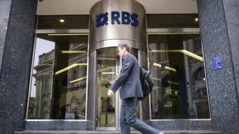 Getty Images A commuter walks past a branch of RBS bank