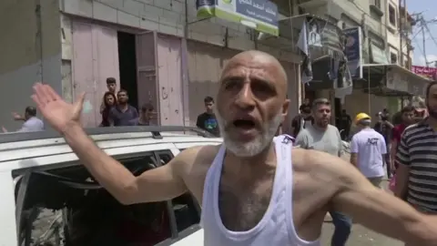 Reuters A man talks to media standing next to a car that was hit by rockets