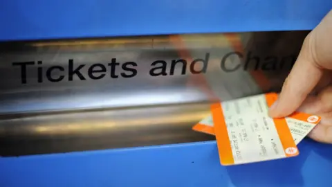 PA Media Person taking train tickets out of a ticket machine