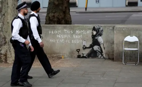 Reuters Police officers walking past mural