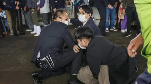 Reuters Three men hold another man down