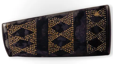 MNH A decorated jet bead before sand has been removed