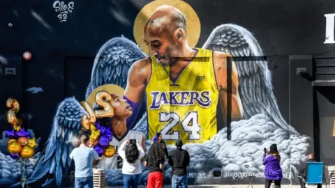 Fans gather at a mural of Kobe Bryant and his daughter Gianna, painted on the wall of Hardcore Fitness Bootcamp gym in downtown Los Angeles.