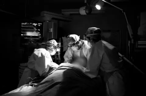 BBC Dr Rattray and team gently lift a patient’s head to improve his breathing.