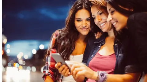 Getty Images Teenage girls looking at a phone