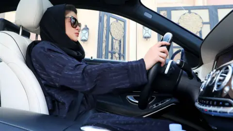 AFP A Saudi woman sat in the driver's seat of a car