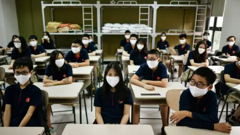 Getty Images Students at their desks wearing masks at a school in Hanoi, Vietnam (4 May 2020)