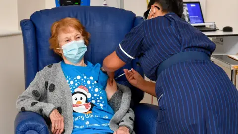Reuters Margaret Keenan, 90, is the first patient in Britain to receive the Pfizer/BioNtech COVID-19 vaccine at University Hospital, administered by nurse May Parsons, at the start of the largest ever immunisation programme in the British history, in Coventry,
