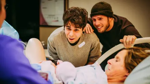 Ariel Panowicz / www.arielpanowicz.com Parents Elliot Dougherty and Matthew Eledge meet their newborn daughter at the hospital.