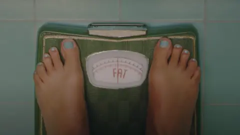 Taylor Swift A screenshot from the music video showing bathroom scales that read FAT