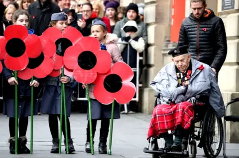 PA Wire children with poppies and war veteran