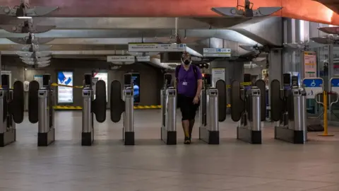 Getty Images A man wearing a full face mask walks out of Westminster underground train station on April 17, 2020 in London, United Kingdom