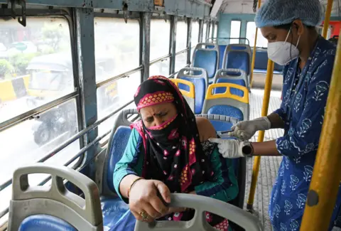 Getty Images A health worker administers Covid vaccine to a woman in a bus in Maharashtra