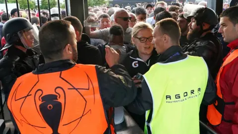 PA Media Fans waiting outside the gates to enter the stadium as kick off is delayed before the UEFA Champions League Final