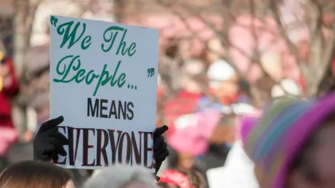 Getty Images Cropped hands holding placard saying 'we the people means everybody'