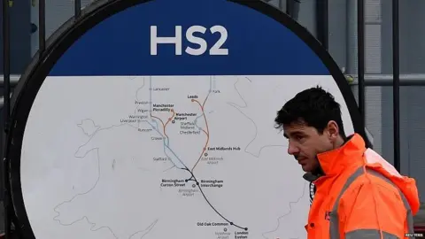 Reuters HS2 worker walks past board showing route of the rail line