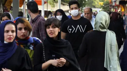 EPA Iranians walk down a street in Tehran (3 June 2020)