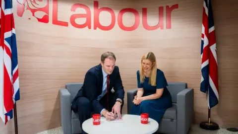 Labour Party Dan Poulter MP signs his Labour membership with the Labour Party deputy national campaign coordinator, Ellie Reeves MP