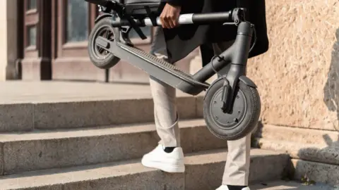 Getty Images Unrecognizable young man carrying an electric push scooter up the stairs