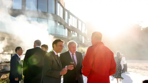  Andrew Parsons/No 10 Emmanuel Macron and Boris Johnson chat with Red Arrows official at G7 summit