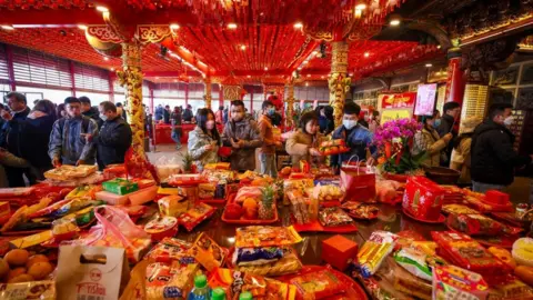 EPA Dozens of people placing food on a table in a temple for Lunar New Year