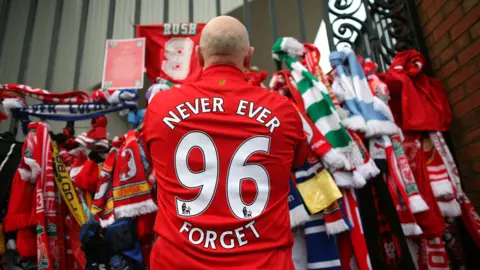 Getty Images Fan lays tribute on gate - his shirt says "never ever forget - 96"