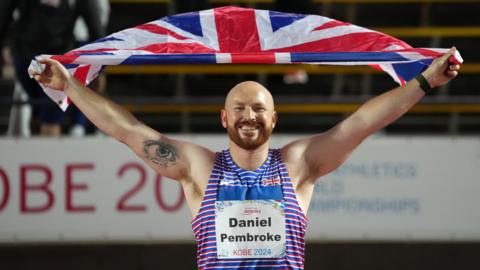 Dan Pembroke holds the Union flag above his head in celebration after winning javelin gold at the World Para Athletics Championships