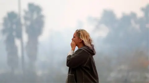 Reuters A woman reacts as the Woolsey Fire burns in Malibu, California,