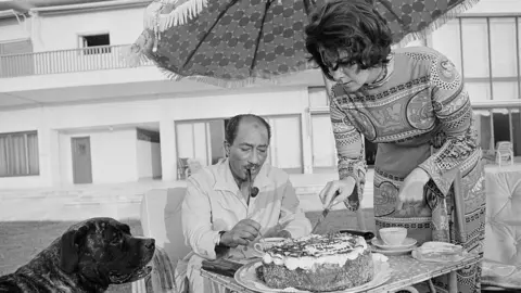 Getty Images Egyptian President Anwar Sadat has cake and tea with his wife Jehan at their summer home in Alexandria 29 July 1972