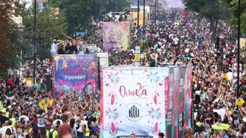 Henry Nicholls Different music buses weave through crowds during the parade