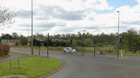 A road junction with a white car sitting at traffic lights