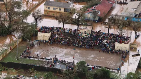 AFP People in the flooded Mozambique town of Buzi stranded on a football stand.