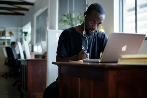 Getty Images Young black South African sits at a computer