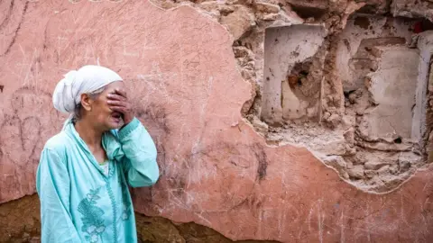 Getty Images A woman standing in front of her earthquake-damaged home in Marrakesh on 9 September