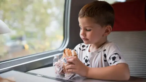 Getty Images Boy eating sandwich on train