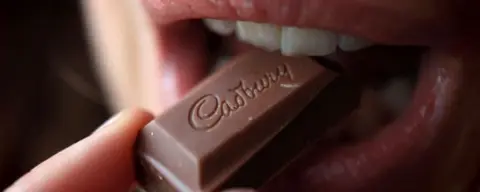 Getty Images Woman tasting a chunk of Cadbury's chocolate