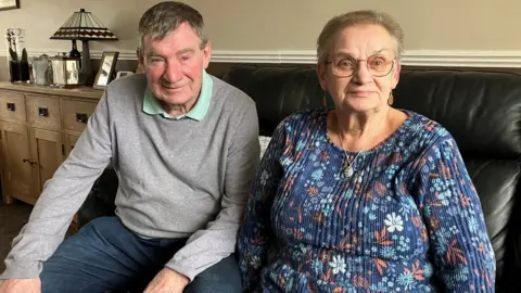 A man and woman sit on a sofa