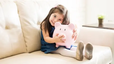 Getty Images Girl with piggy bank