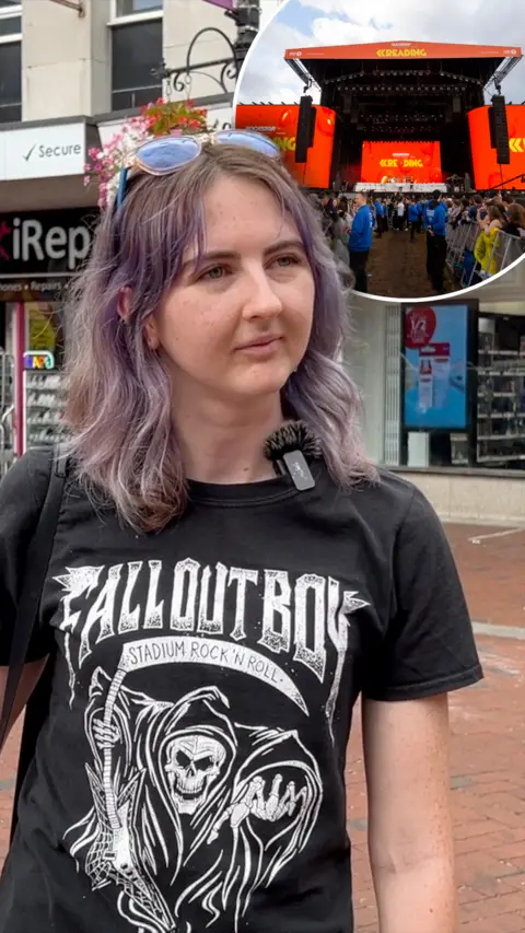 A girl with short light purple hair and a black t-shirt which says 'Fallout Boy' on the front.